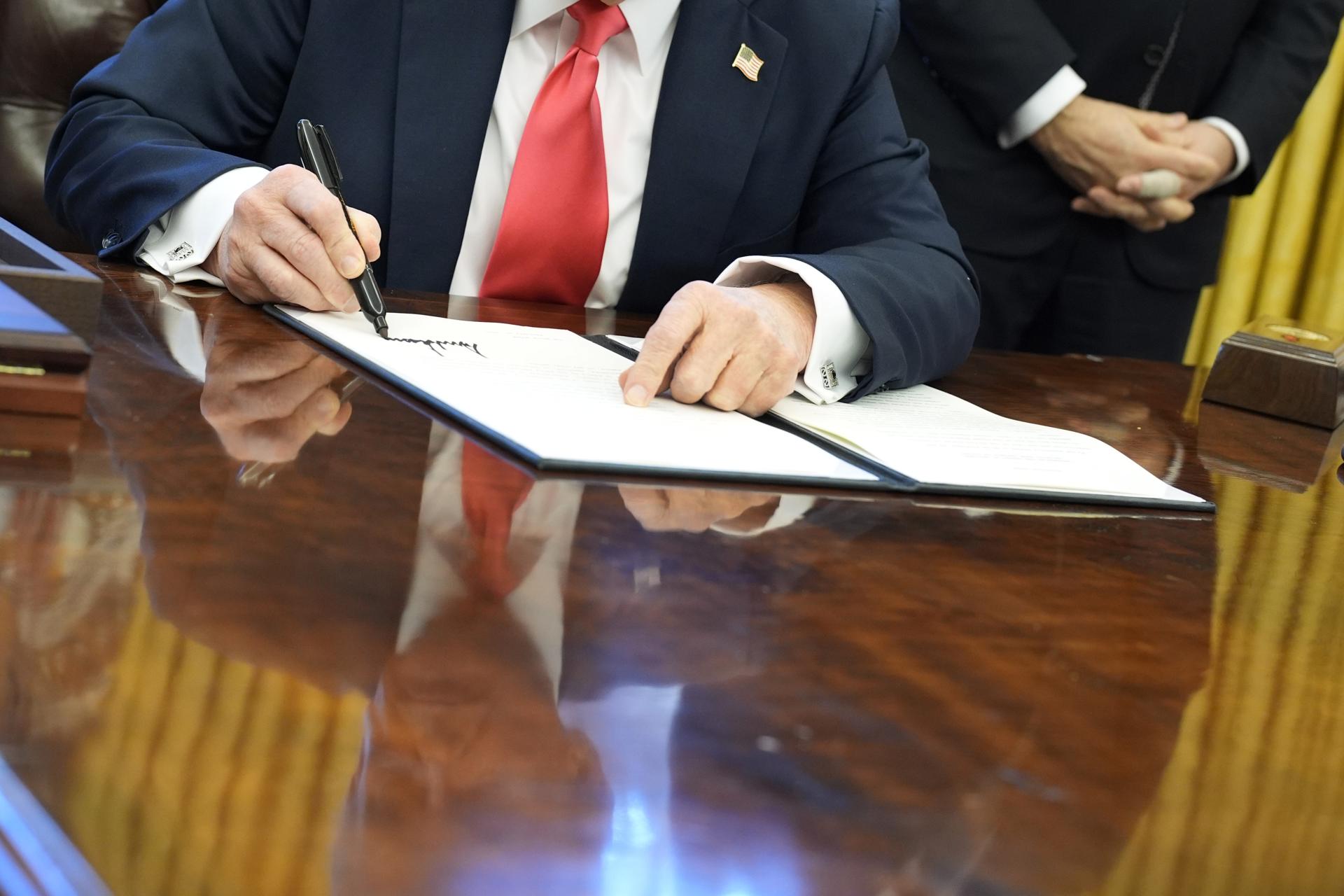 Fotografía de las manos del presidente de Estados Unidos, Donald Trump, firmando una orden ejecutiva en La Casa Blanca en Washington (EE.UU.). Foto: EFE/Yuri Gripas POOL